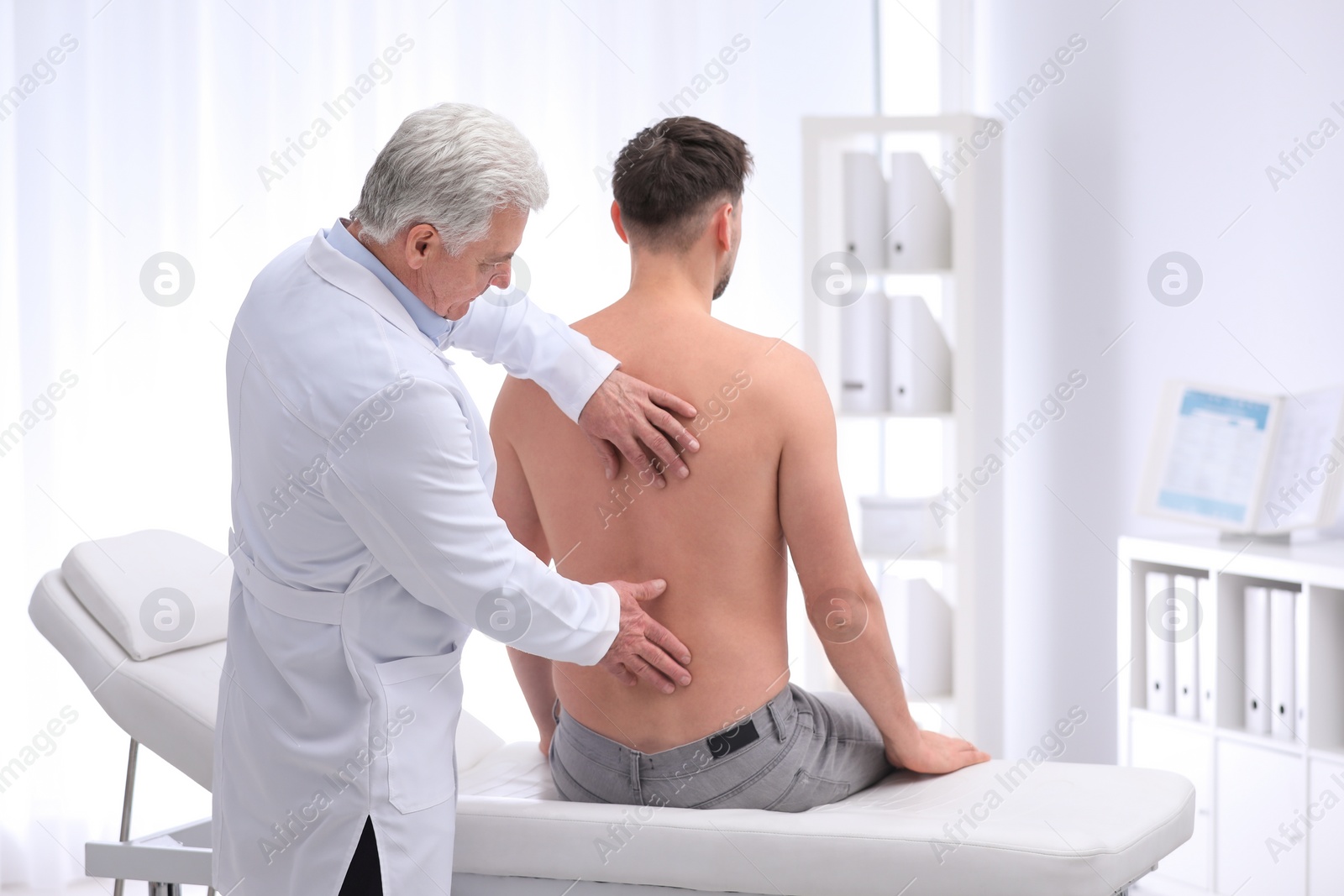 Photo of Chiropractor examining patient with back pain in clinic