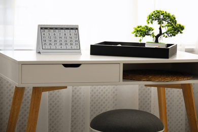 Photo of Paper calendar and bonsai tree on white table indoors