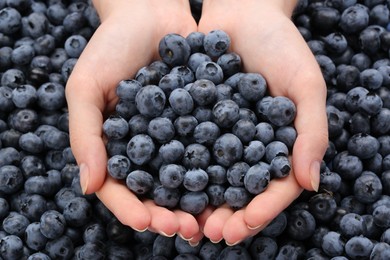 Photo of Woman holding heap of juicy fresh blueberries, closeup