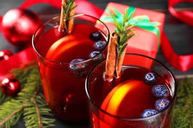 Photo of Aromatic Sangria drink in glasses, ingredients and Christmas decor on table, closeup