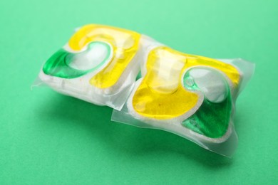 Photo of Two dishwasher detergent pods on green background, closeup