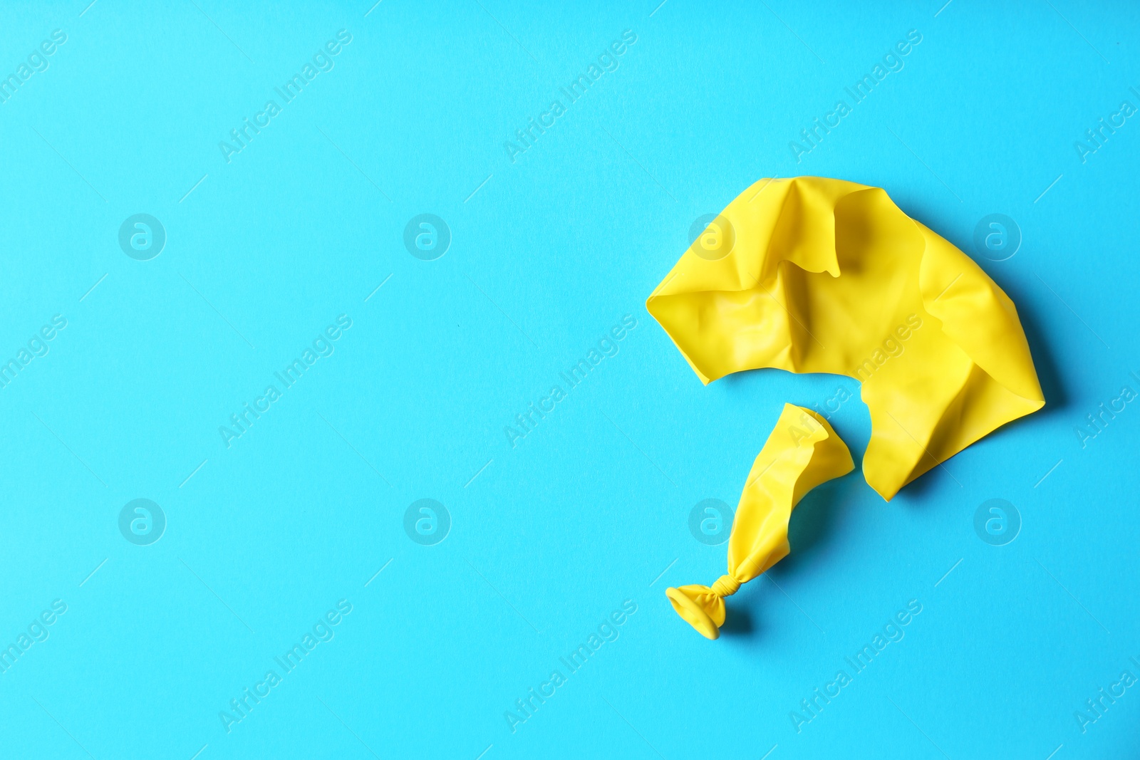 Photo of Popped balloon on color background, top view with space for text