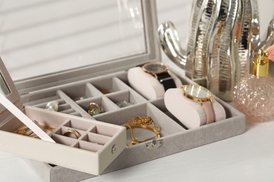 Photo of Jewelry boxes with many different accessories and perfume on white wooden table, closeup