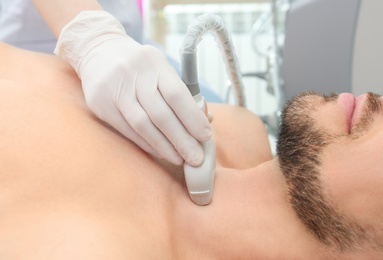 Photo of Doctor conducting ultrasound examination of thyroid gland in clinic