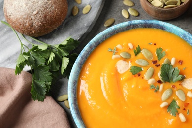 Delicious pumpkin soup in bowl on grey table, top view