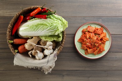 Photo of Delicious kimchi with Chinese cabbage and ingredients on wooden table, flat lay