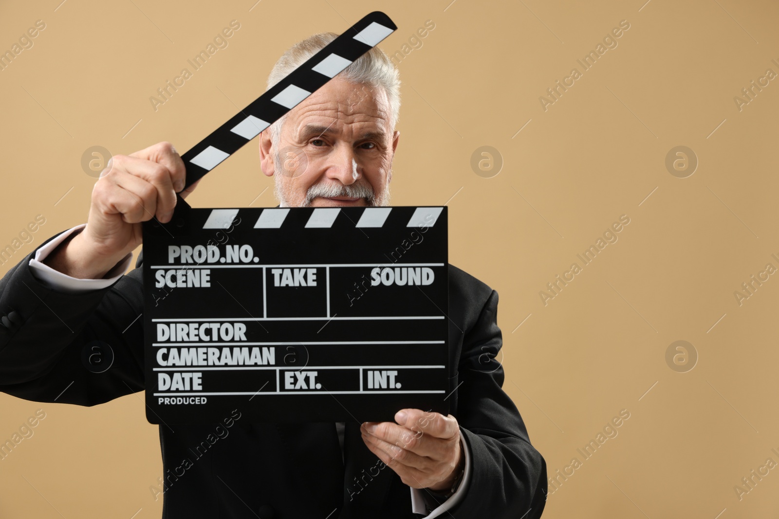 Photo of Senior actor holding clapperboard on beige background, space for text. Film industry