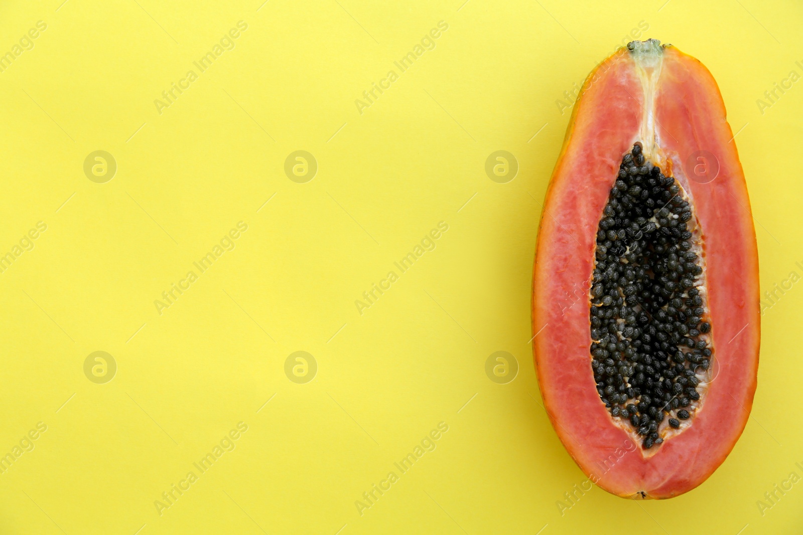 Photo of Half of fresh ripe papaya fruit on light green background, top view. Space for text