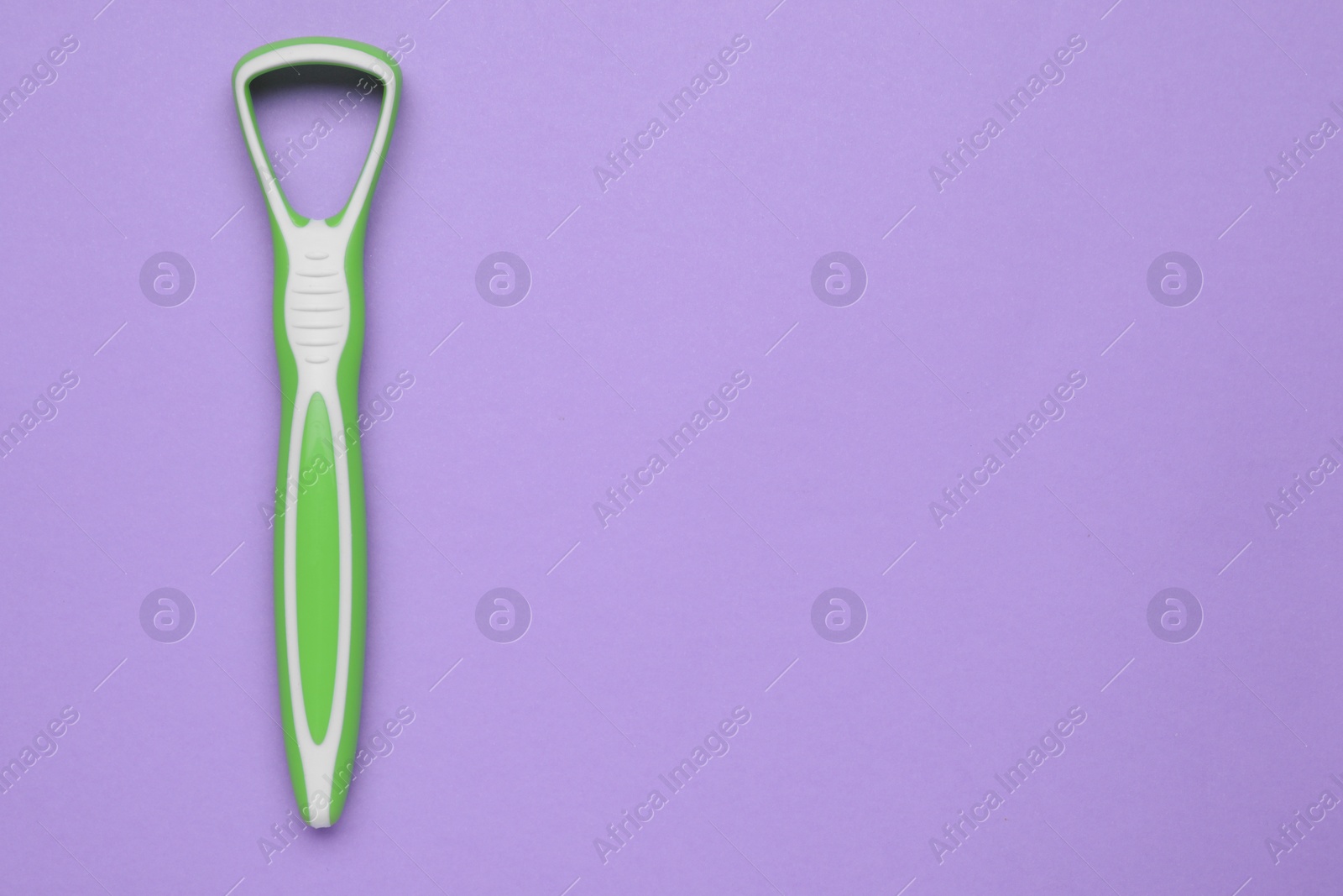 Photo of Green tongue cleaner on violet background, top view. Space for text