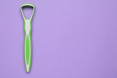 Photo of Green tongue cleaner on violet background, top view. Space for text