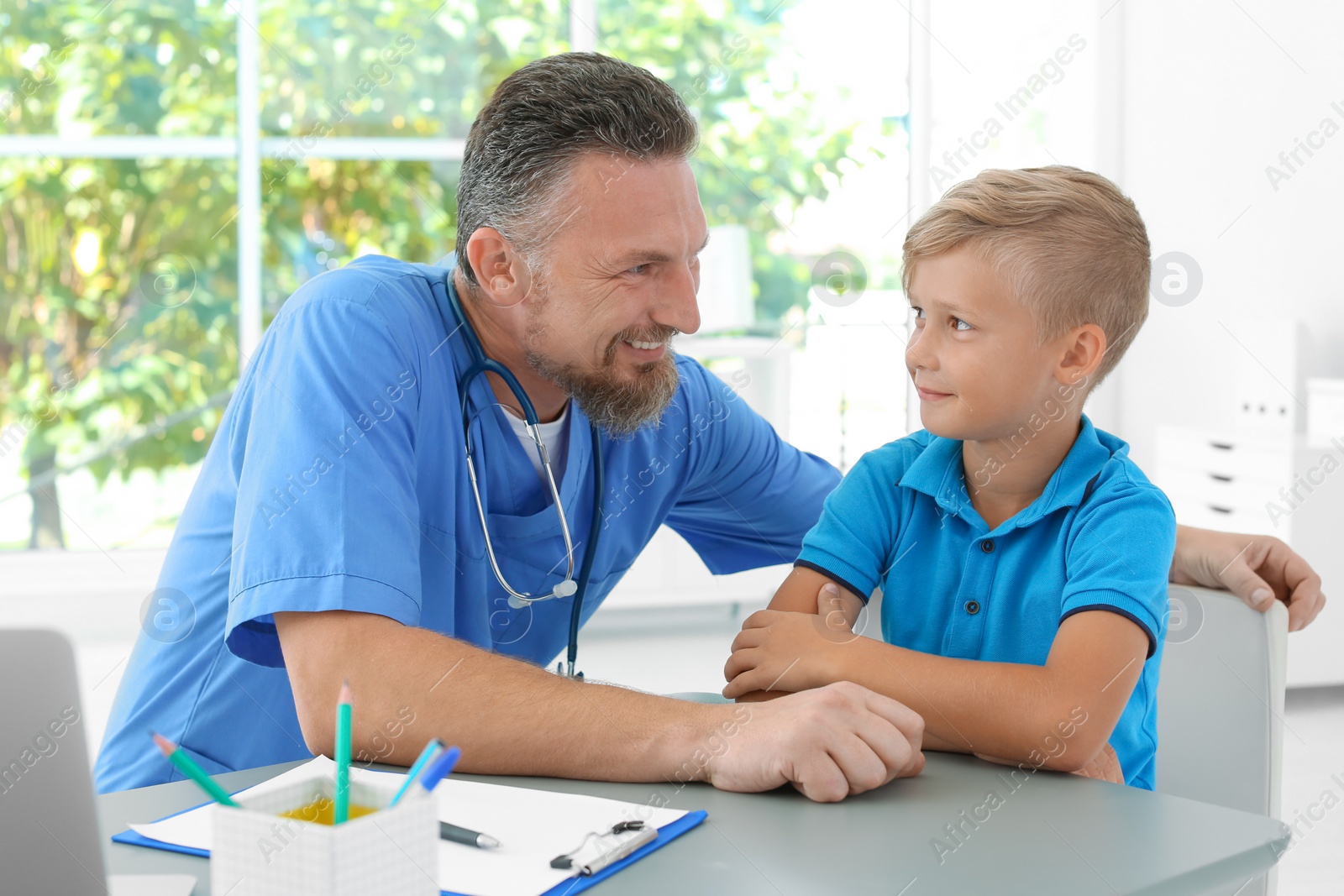 Photo of Male medical assistant consulting child in clinic