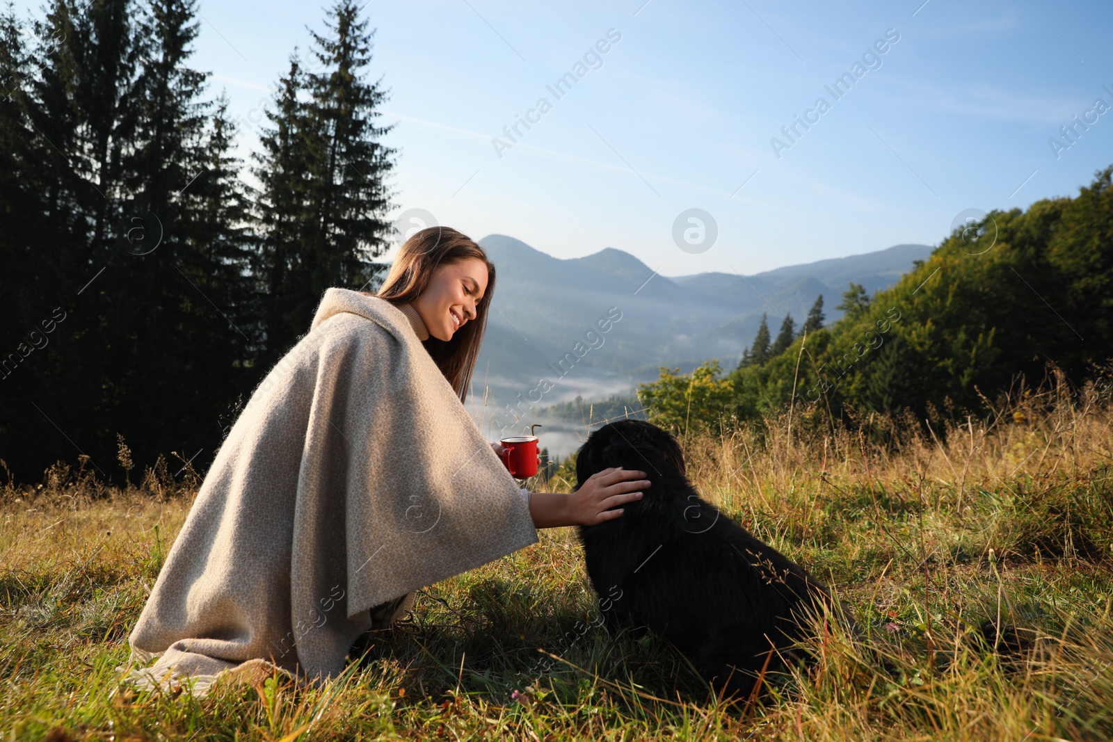 Photo of Young woman enjoying time with her dog in mountains