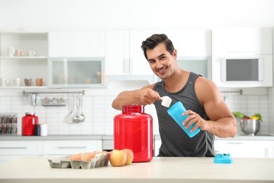 Young athletic man preparing protein shake in kitchen, space for text