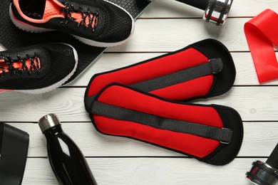 Photo of Red weighting agents and sport equipment on white wooden table, flat lay