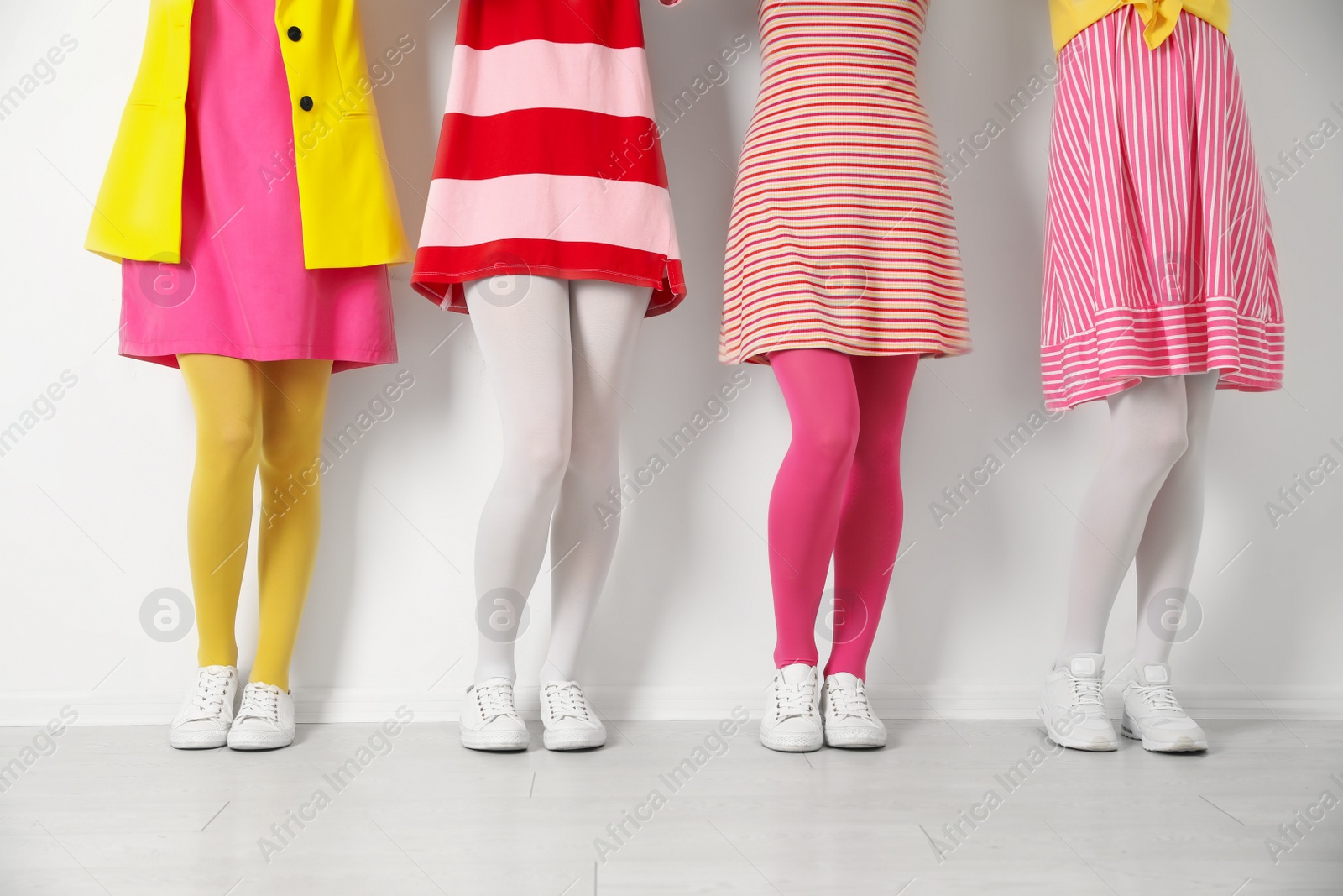 Photo of Women wearing colorful tights near white wall, closeup