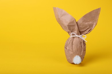 Photo of Easter bunny made of kraft paper and egg on yellow background. Space for text