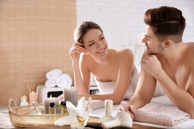 Young couple with spa essentials in wellness center