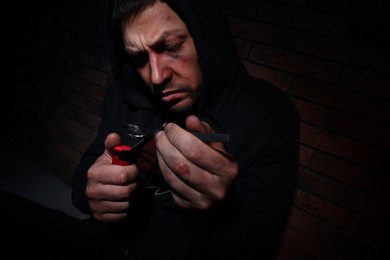 Photo of Man preparing drug with spoon and lighter near brick wall