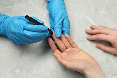 Diabetes. glucose testing. Doctor using lancet pen at light table, closeup