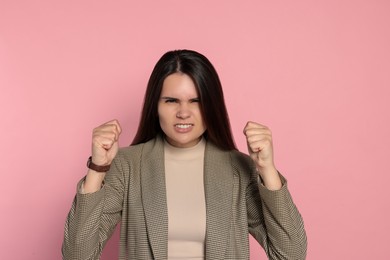 Photo of Aggressive young woman showing fists on pink background