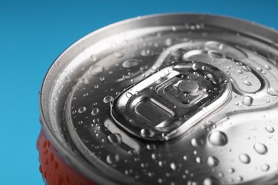 Photo of Energy drink in wet can on light blue background, closeup