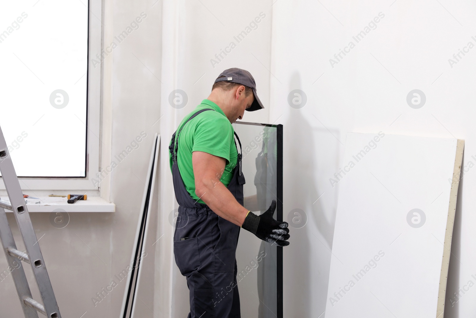 Photo of Worker in uniform taking double glazing window indoors