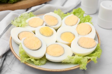 Photo of Fresh hard boiled eggs and lettuce on white marble table