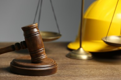 Construction and land law concepts. Gavel, scales of justice and hard hat on wooden table, closeup
