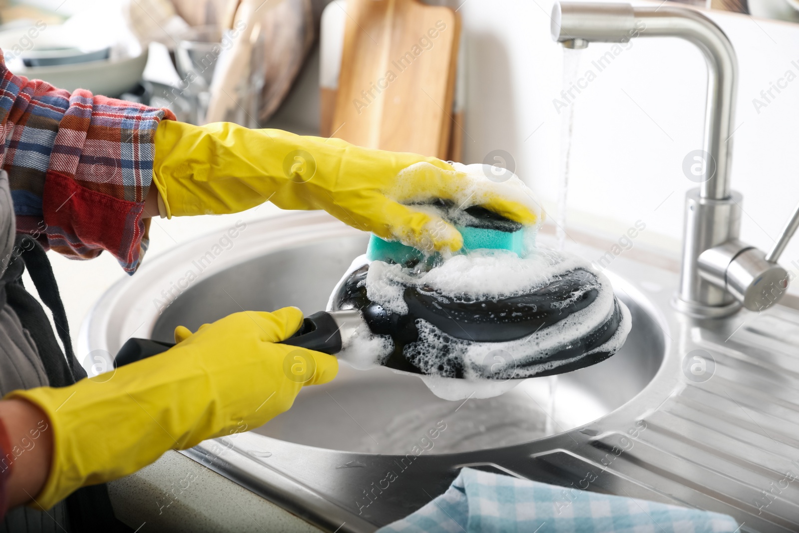 Photo of Woman washing dirty frying pan in sink indoors, closeup