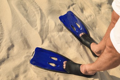Photo of Man in blue flippers on sand, closeup view