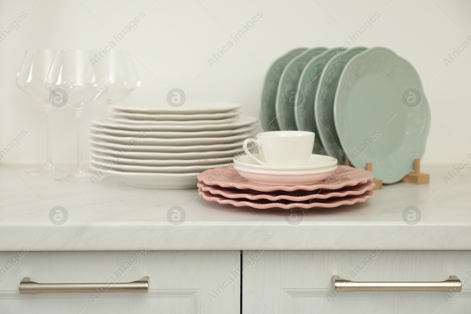 Photo of Clean plates, glasses and cup on white marble countertop in kitchen