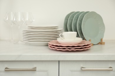 Clean plates, glasses and cup on white marble countertop in kitchen