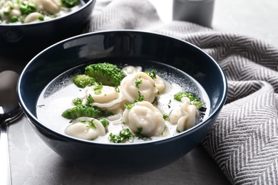 Photo of Tasty dumplings in broth served on grey table