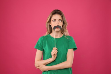 Photo of Young woman with fake mustache on pink background