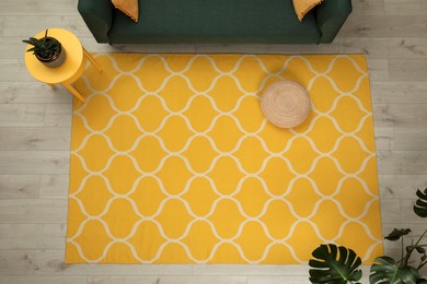 Yellow carpet with geometric pattern on wooden floor in living room, above view