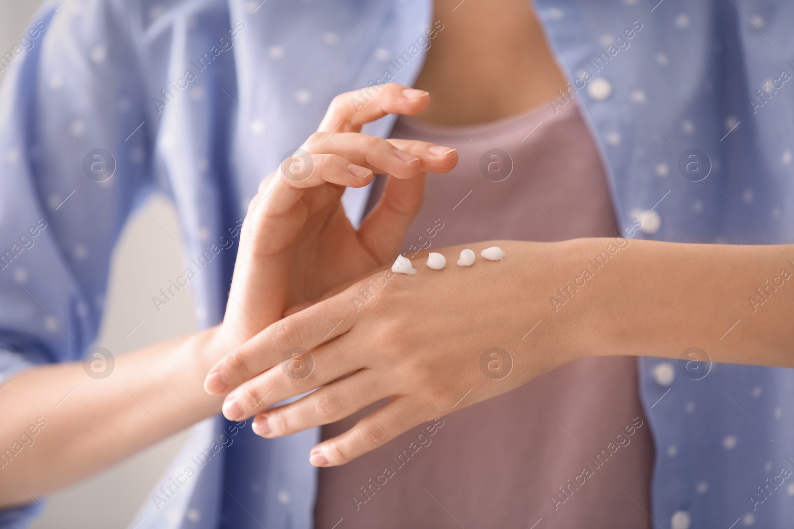 Photo of Young woman applying hand cream, closeup