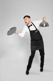 Photo of Clumsy waiter dropping empty tray on light background