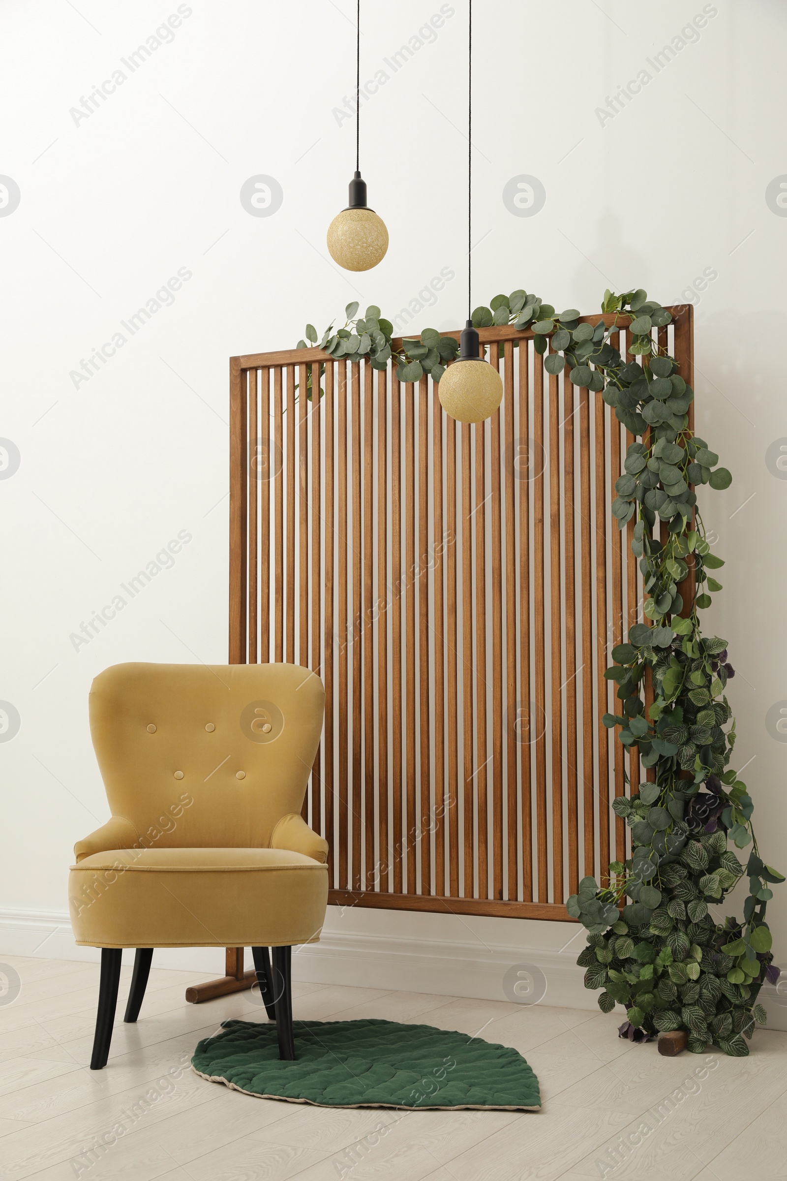 Photo of Stylish photo zone with wooden screen, floral decor and comfortable armchair indoors