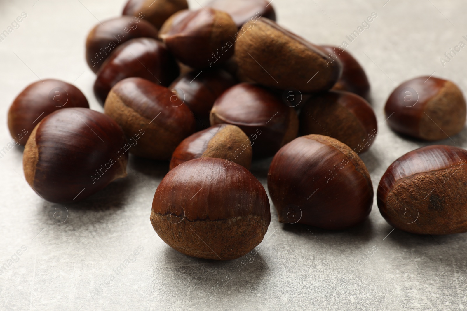Photo of Roasted edible sweet chestnuts on light grey table, closeup