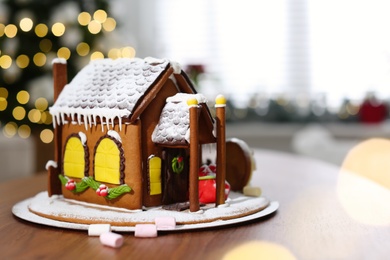 Photo of Beautiful gingerbread house decorated with icing on wooden table indoors, space for text