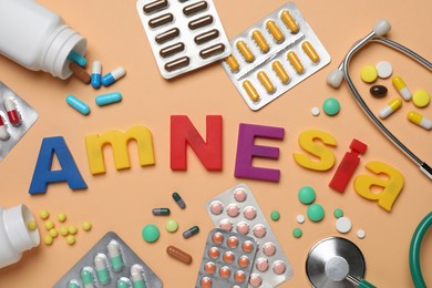Photo of Word Amnesia made of colorful letters and drugs on orange background, flat lay