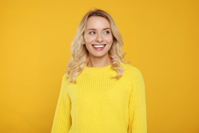 Photo of Happy woman in stylish warm sweater on orange background