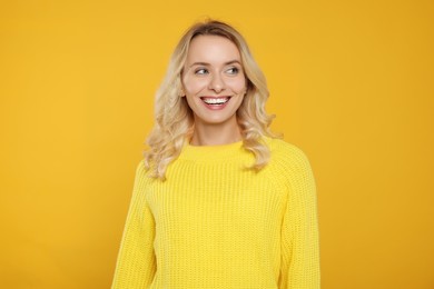 Happy woman in stylish warm sweater on orange background