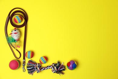 Flat lay composition with pet leash and toys on yellow background, space for text