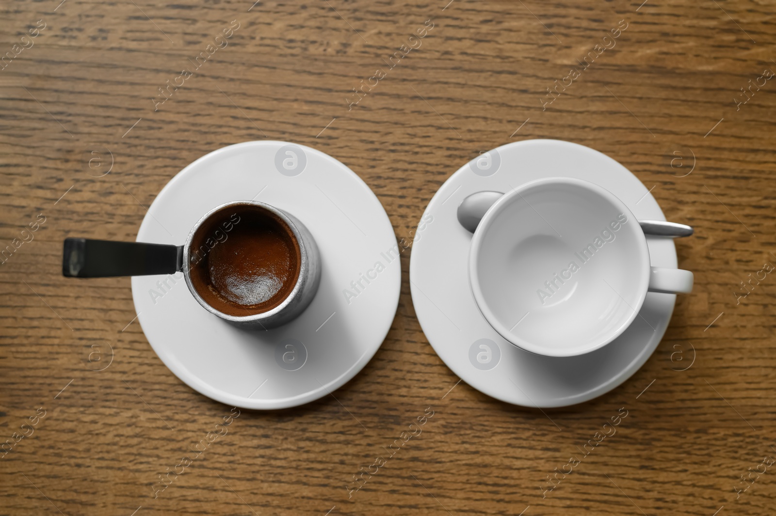 Photo of Jezve with fresh coffee and empty cup on wooden table, flat lay