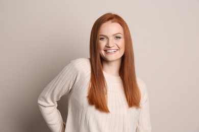 Photo of Candid portrait of happy young woman with charming smile and gorgeous red hair on beige background