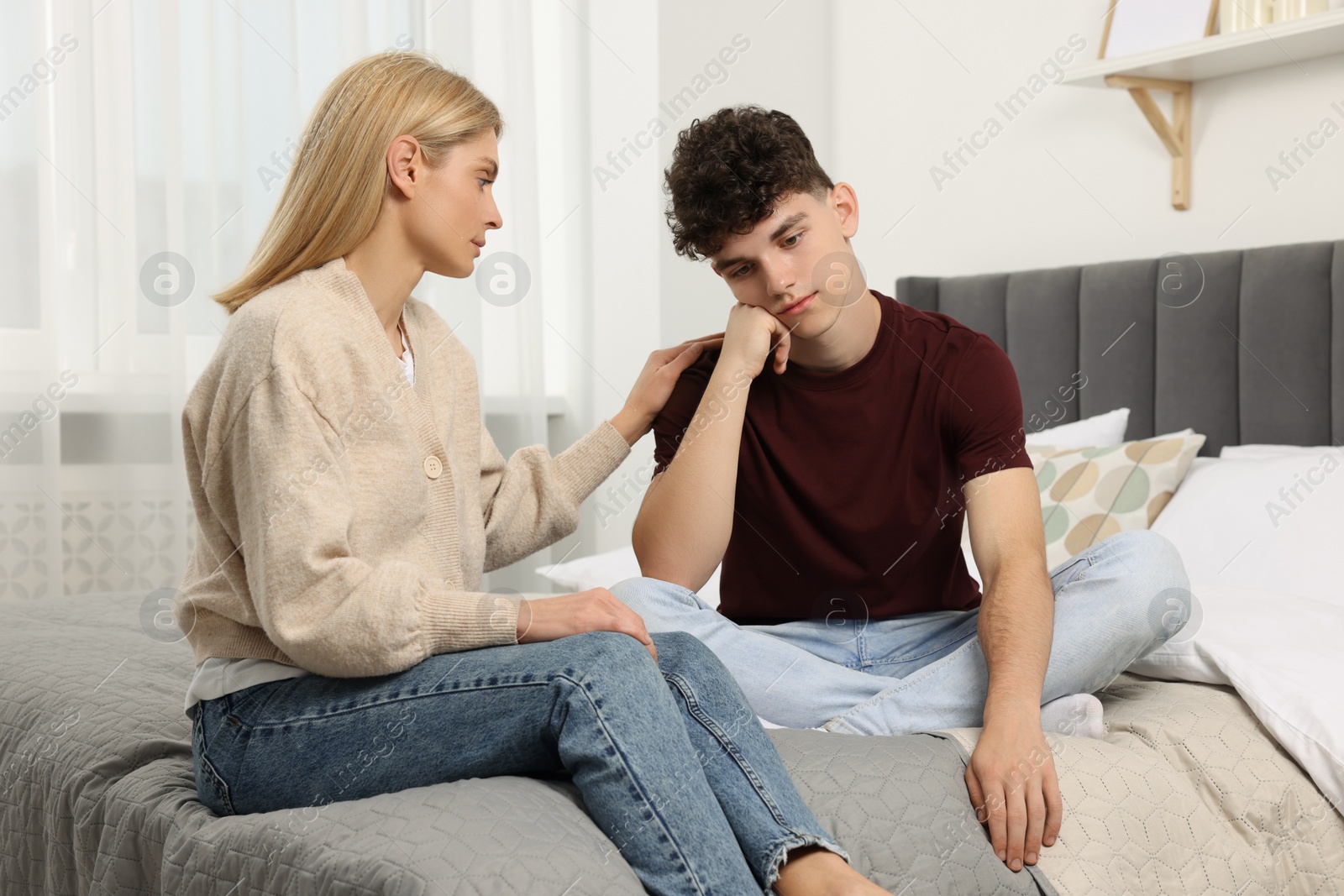 Photo of Mother consoling her upset son in bedroom. Teenager problems