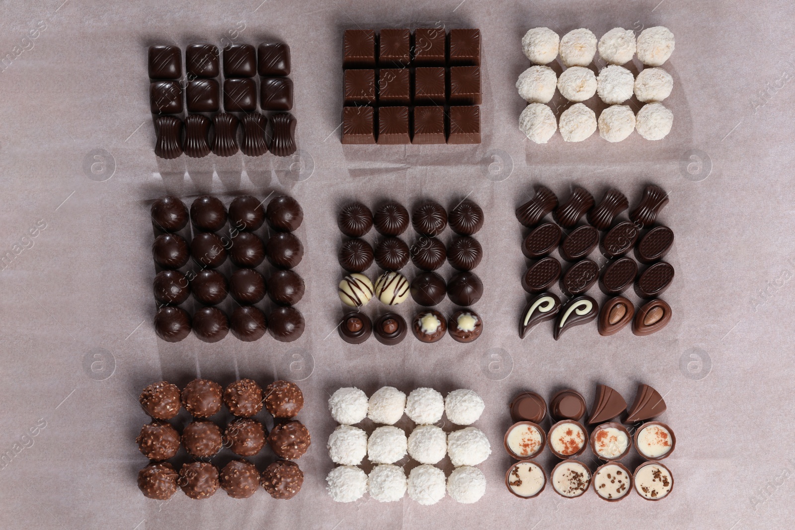 Photo of Many delicious chocolate candies on table, flat lay. Production line