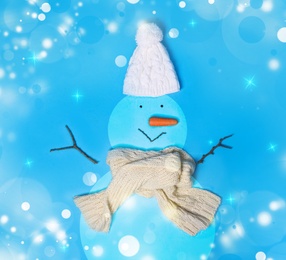 Image of Snowman with hat and scarf on light blue background, flat lay. Bokeh effect 