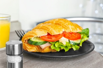 Photo of Tasty croissant sandwich with sausage on table